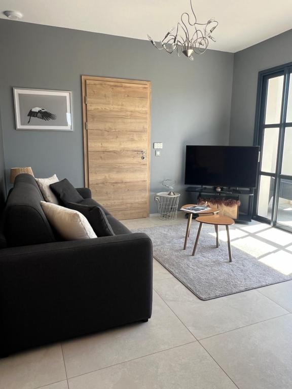 a living room with a black couch and a tv at Schlof'zheim in Friesenheim