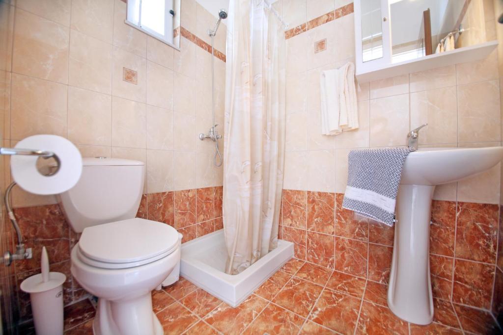 a bathroom with a toilet and a sink and a shower at Kos Island Studios in Kefalos