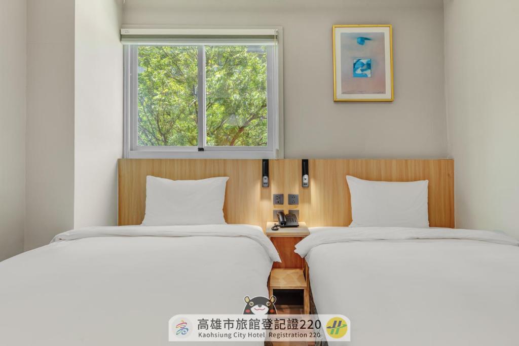 two beds in a room with a window at Whiyori Inn in Kaohsiung