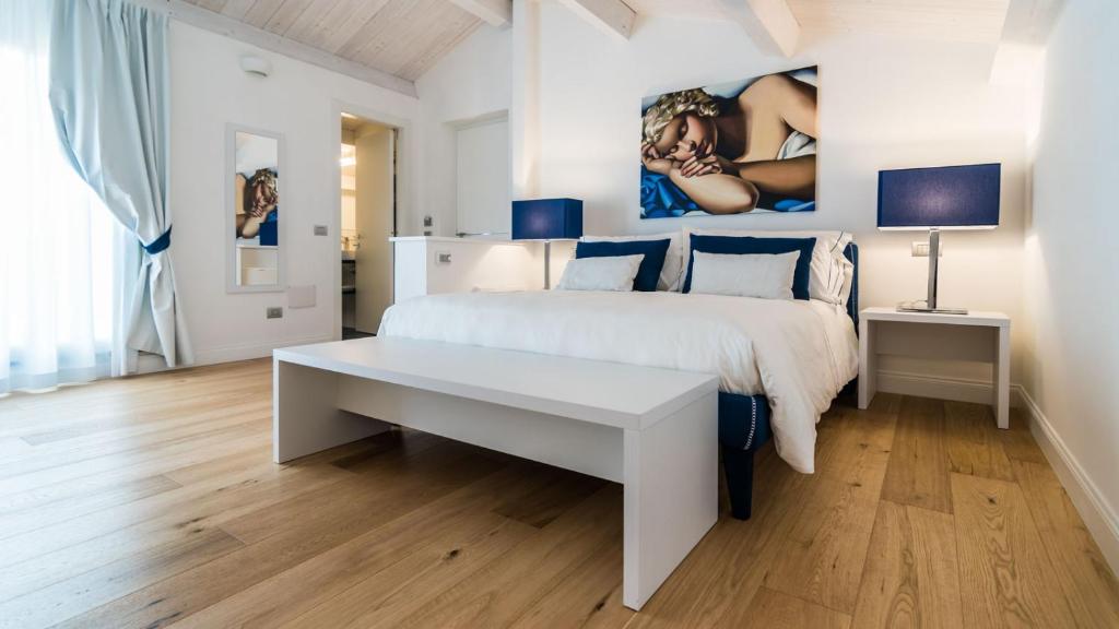 a white bedroom with a white bed and a table at Deki Relais in Sassari