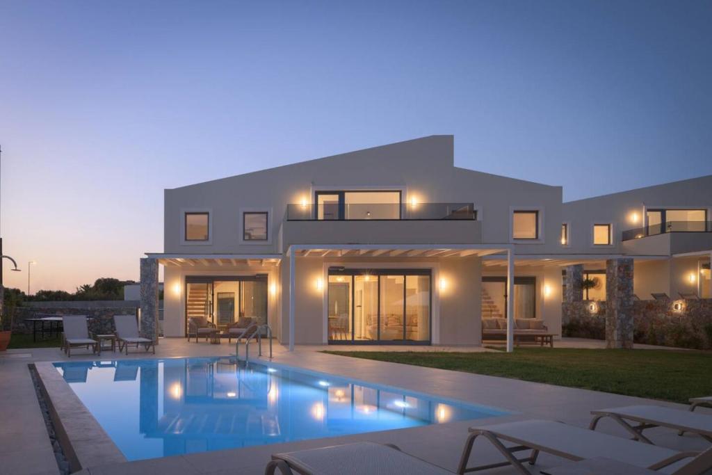 a villa with a swimming pool at dusk at Pelagia's Loft Villas Haroupi & Rodi with Private Heated Pools, 5 Walking Distance to the Beach in Kavros