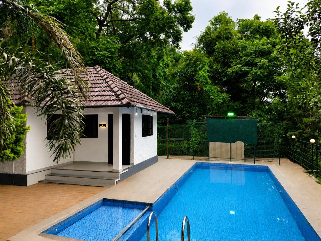 a small swimming pool next to a small house at Riva Resorts in Vythiri