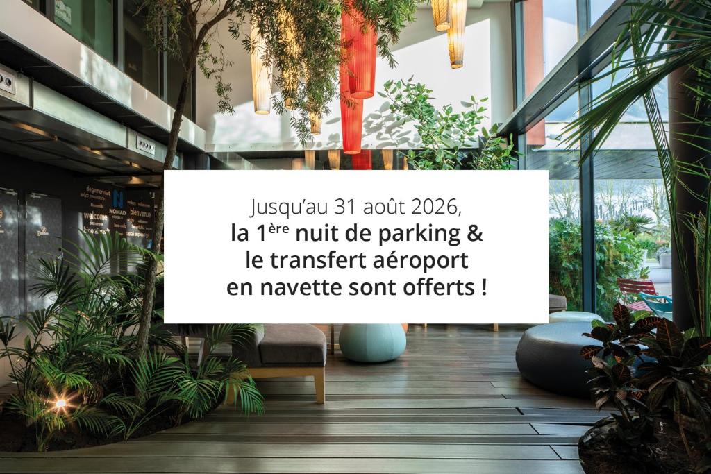 a sign on the side of a building with plants at Nomad Paris Roissy CDG in Le Mesnil-Amelot