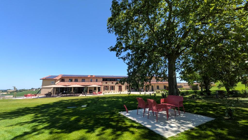 a group of chairs sitting under a tree in front of a building at Lieu-dit Boulage in Marquefave
