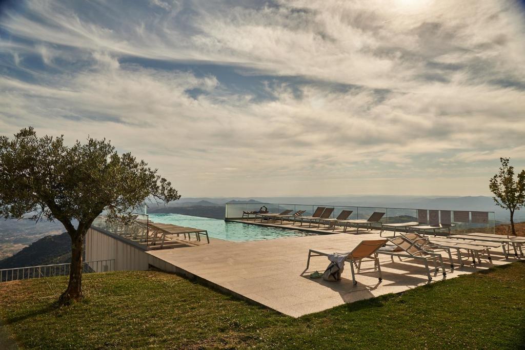 a bench sitting on a deck with a view of the water at Alfândega da Fé Hotel & SPA in Sambade