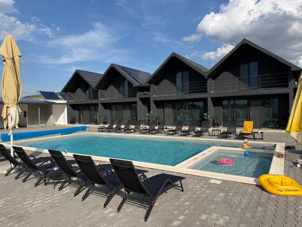 a swimming pool with chairs and a house at La Luna Imobiliare in Ocna-Mureşului