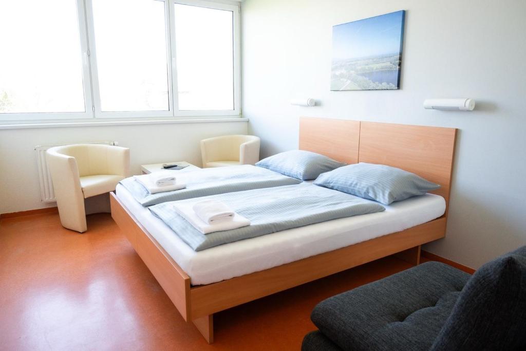 a bedroom with a bed and a chair and windows at Junges Hotel Hard am Bodensee in Hard
