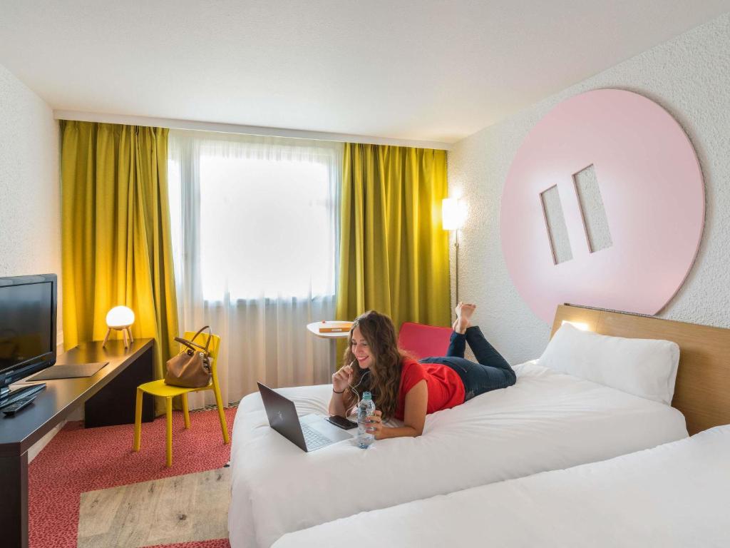 a woman laying on a bed in a hotel room at ibis Styles Lyon Bron Eurexpo in Bron
