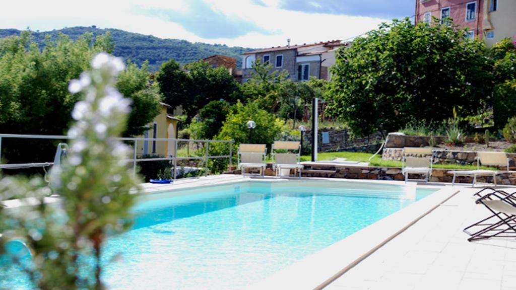 una gran piscina con sillas, árboles y edificios en Agriturismo San Michele di Danio Giovanni en Dolcedo