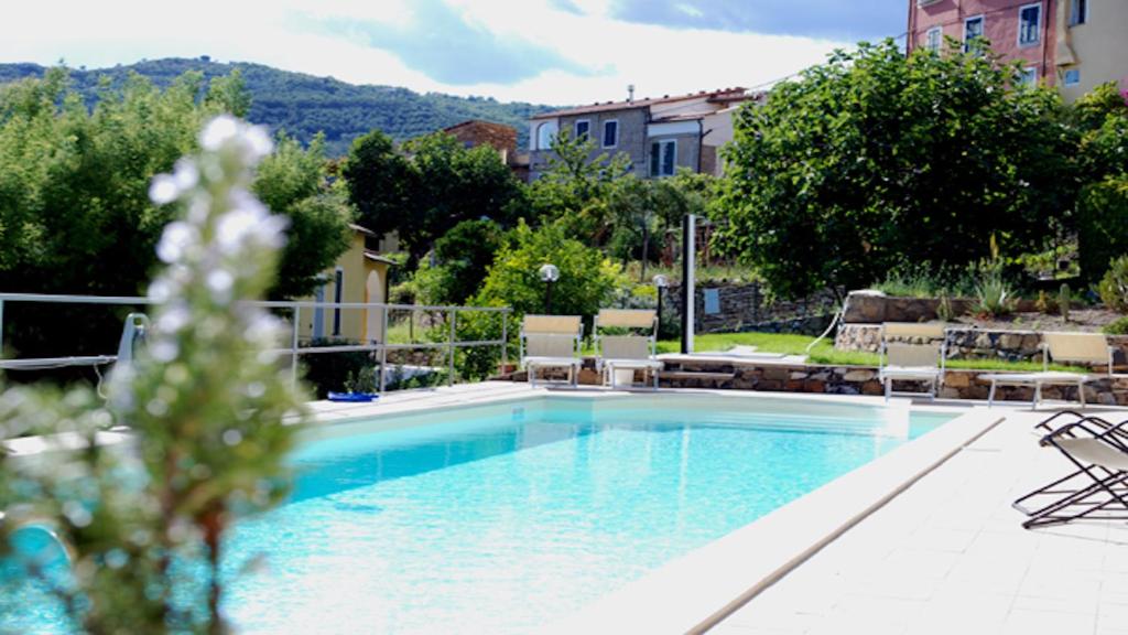 una grande piscina con sedie, alberi ed edifici di Agriturismo San Michele di Danio Giovanni a Dolcedo