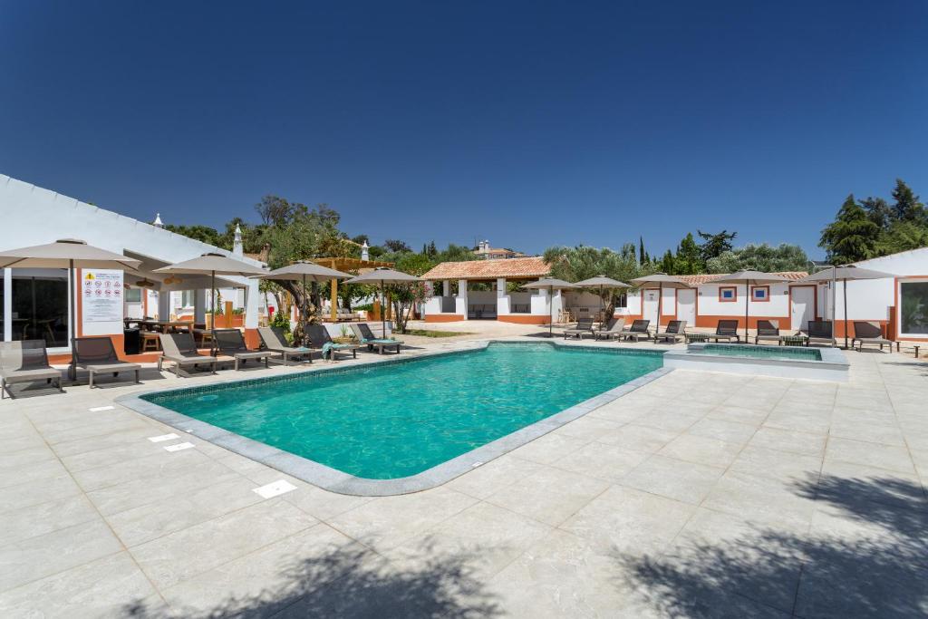 a pool with chairs and umbrellas at a resort at VILLA BRANDA - Tavira Nature Hotel in Tavira