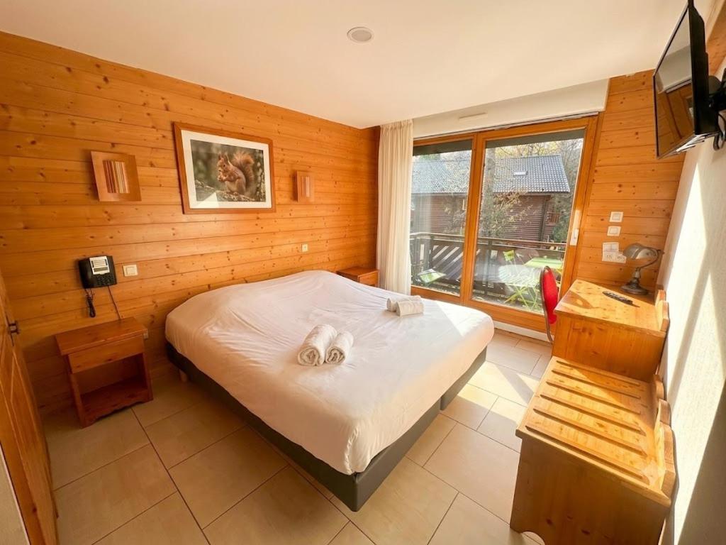 a small bedroom with a bed and a window at Hôtel Résidence La Maison par Les Pins Sylvestres Amnéville les Thermes in Amnéville