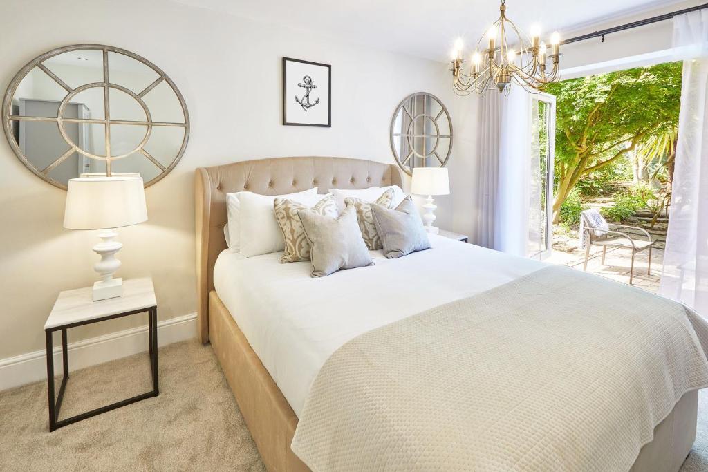 a bedroom with a white bed with a window and a chandelier at The Hampton Garden in Whitby