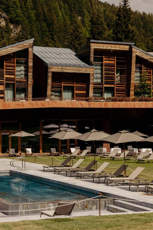 a resort with a pool and chairs and umbrellas at Aethos Hotel Monterosa in Champoluc
