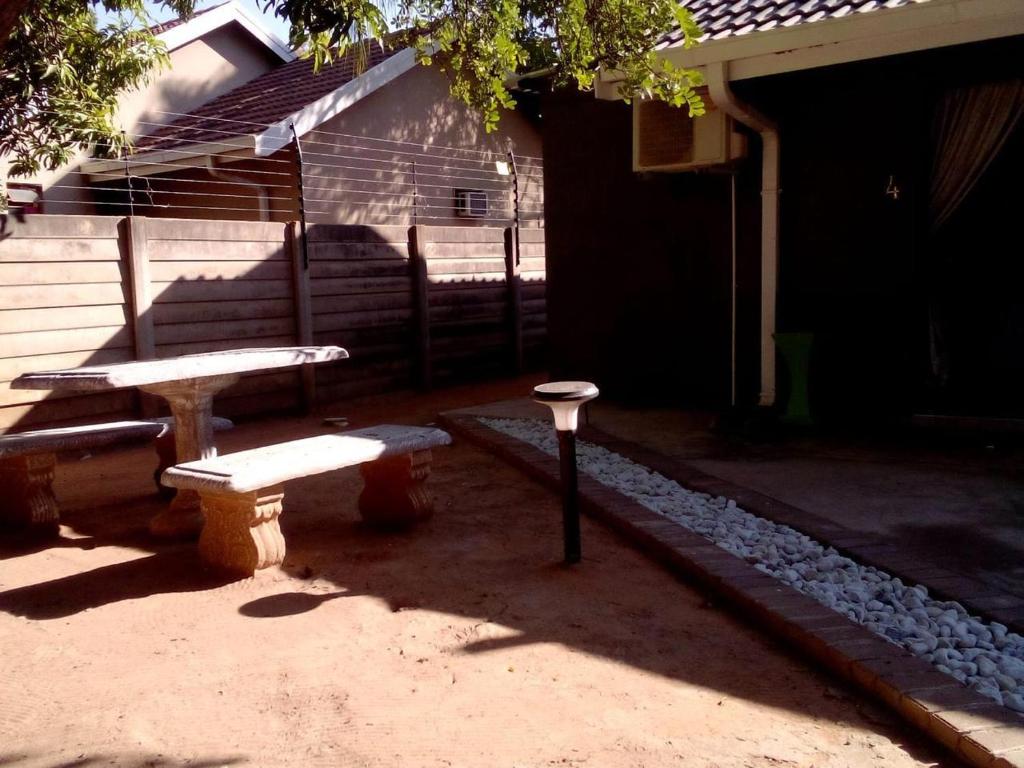 a picnic table and benches in front of a building at Vhulinganela Guest House in Ellisras