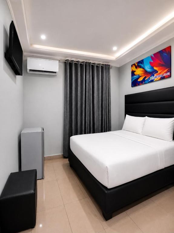 a bedroom with a large white bed and a tv at Metro Lodge MP in Durban