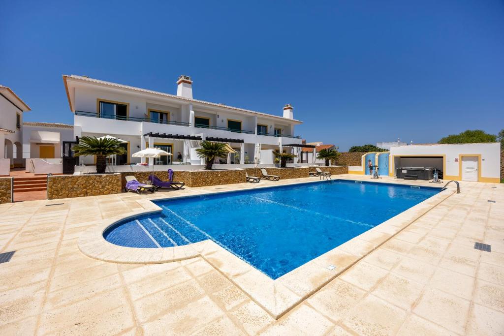 a villa with a swimming pool in front of a house at Casa Iguana in Budens