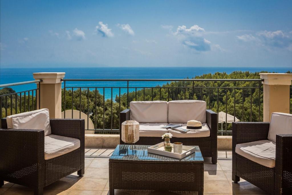 a patio with chairs and a table and the ocean at Aphrodite Blue in Trapezaki