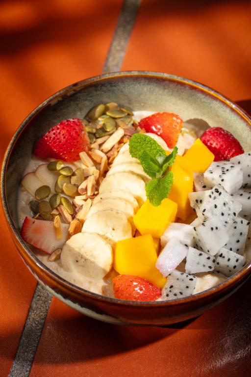A fruit-and-grain breakfast bowl is topped with banana, berries, seeds and tropical fruit.