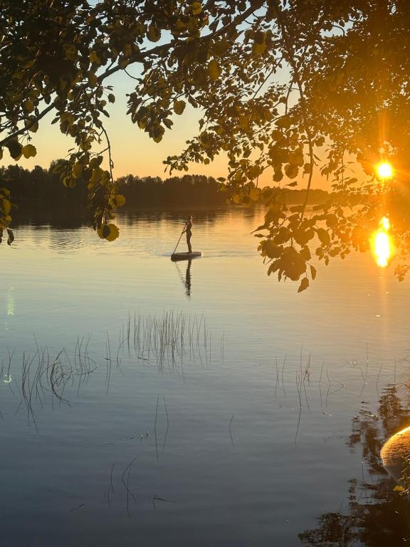 a person is standing on a paddle board in the water at Private Riverside Cabin, Utajärvi in Korhola