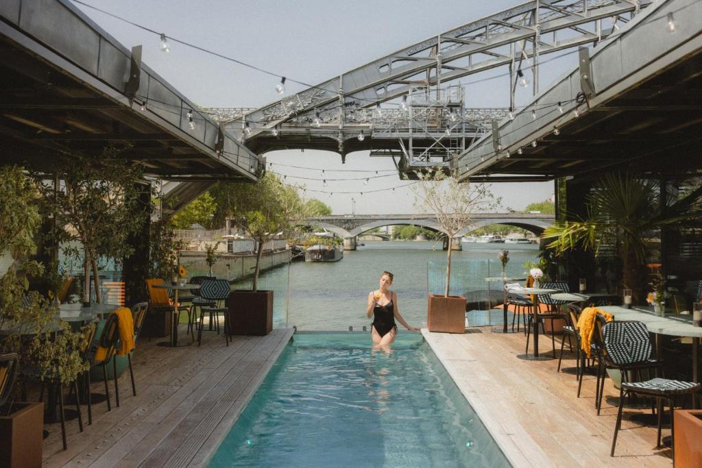 a woman standing in a swimming pool next to a river at Hotel OFF Paris Seine in Paris