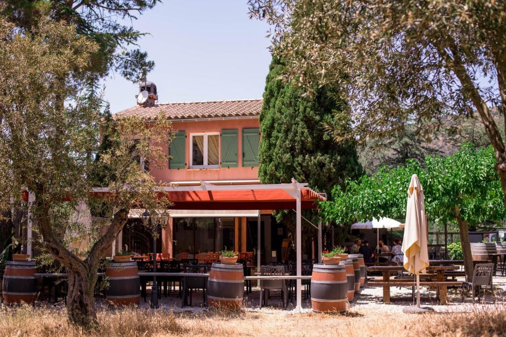 a restaurant with tables and an umbrella in front of a building at Chambres à la Table du Curé in Cucugnan