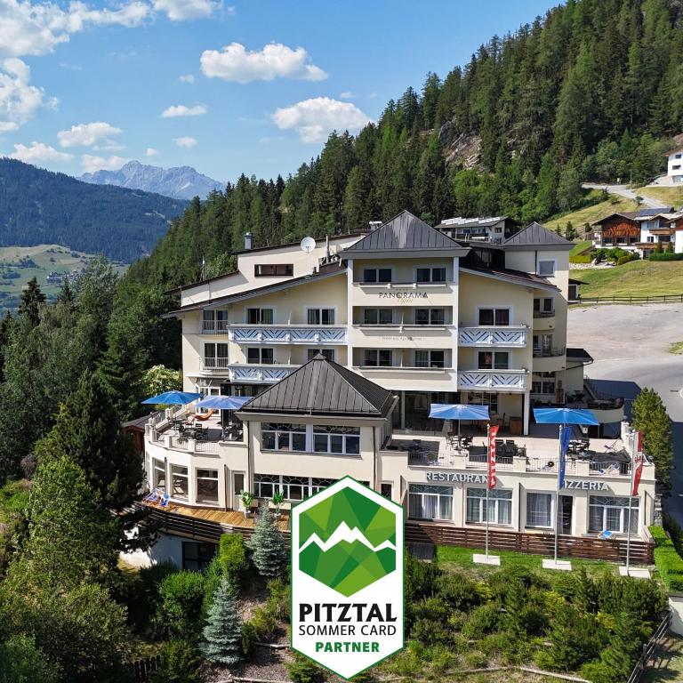 a hotel in the mountains with a sign in front of it at Wellness Aparthotel Panorama Alpin - Ferienwohnungen Jerzens im Pitztal in Jerzens
