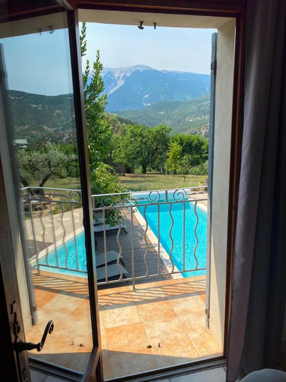 a room with a view of a swimming pool through a sliding glass door at Chambre d'hôtes une fenêtre sur le Ventoux in Plaisians