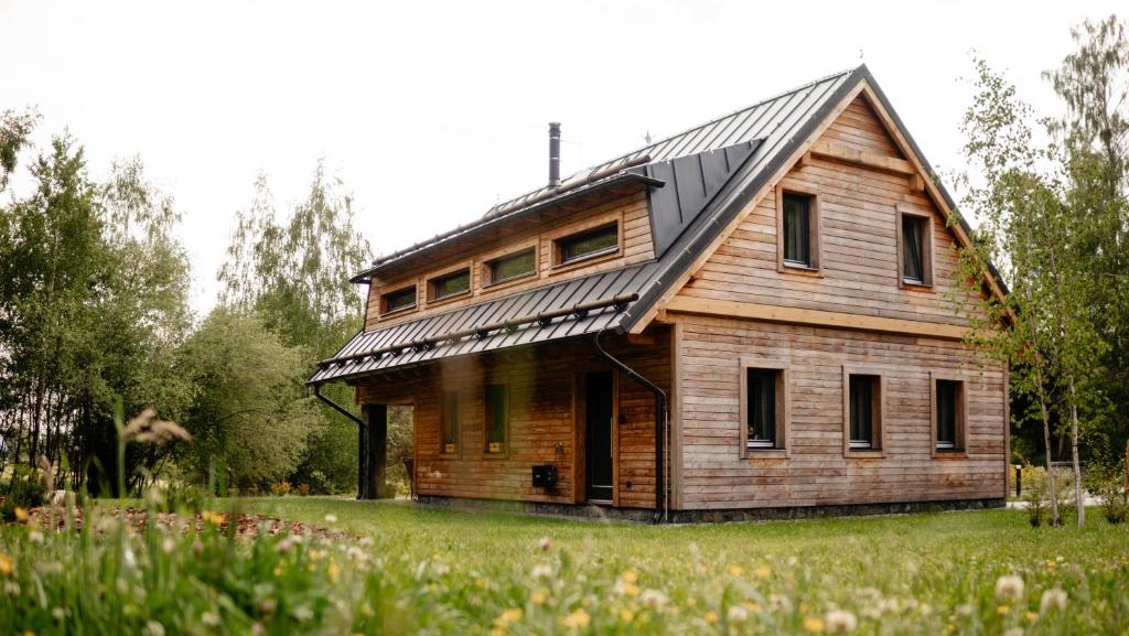 an old wooden house with a metal roof on a field at Vila Sněženka in Horní Planá