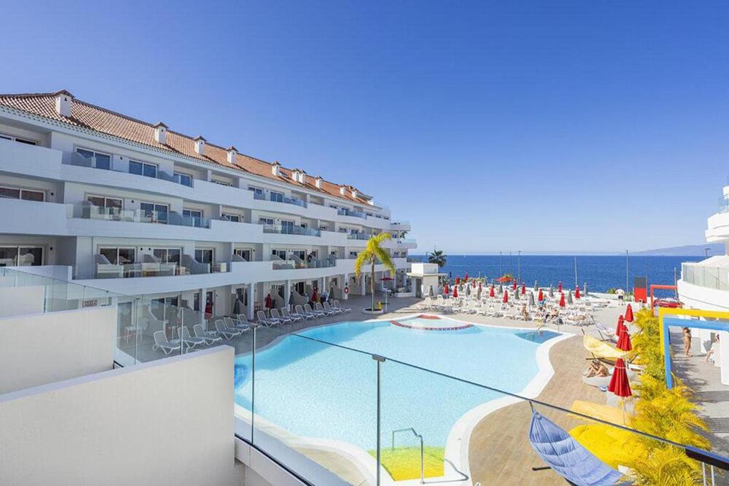 a hotel with a swimming pool and the ocean at Sholeo Lodges Los Gigantes in Puerto de Santiago