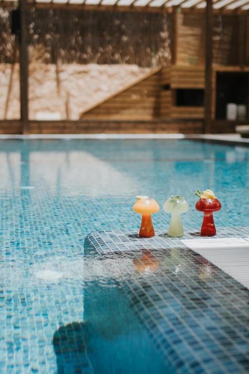 three miniature mushrooms sitting next to a swimming pool at DUNIA Desert Suites in Mitzpe Ramon