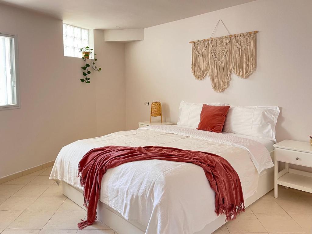 a bedroom with a white bed with a red blanket on it at Galilee Nook in Kefar Weradim