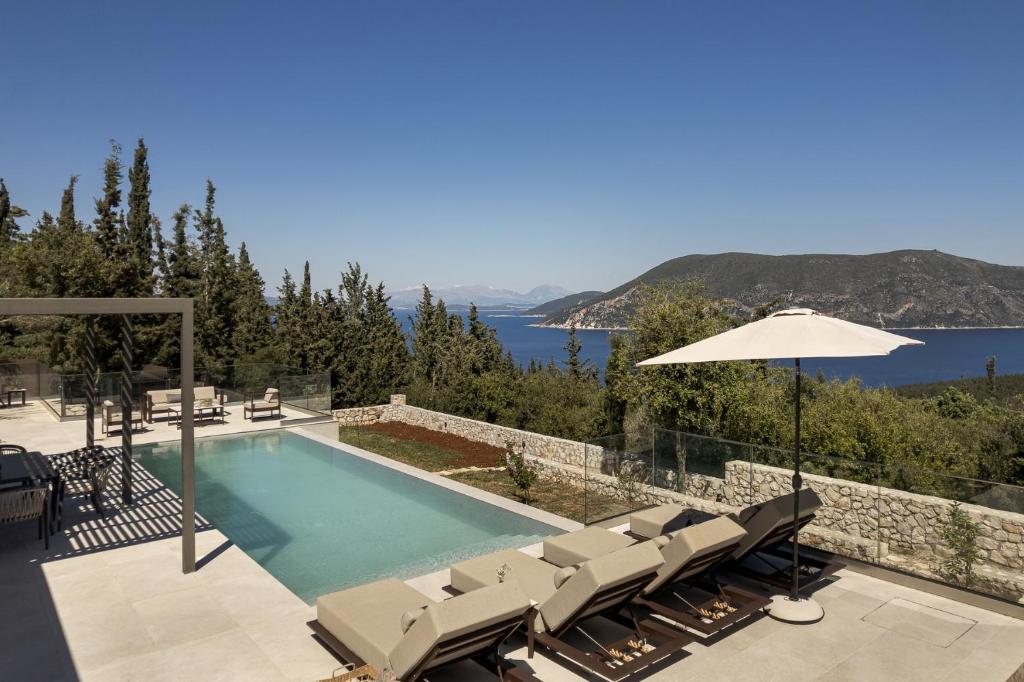 a swimming pool with chairs and an umbrella at Villa Thalassa by Villa Select in Fiskardo