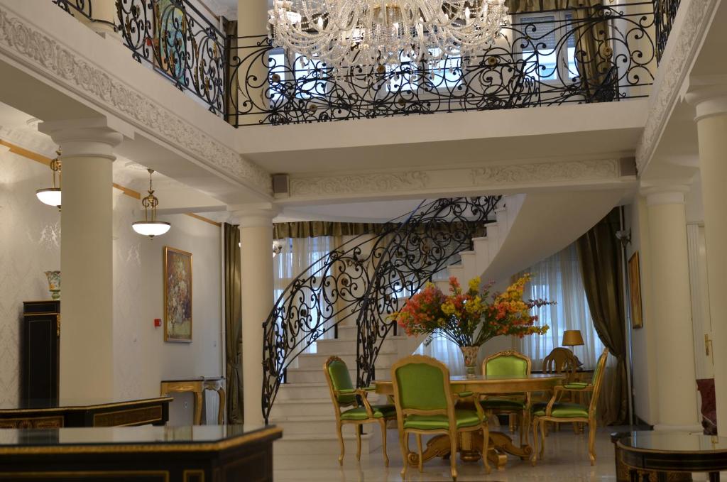 una sala da pranzo con tavolo, sedie e lampadario pendente di Garni Hotel Helvetia a Belgrado