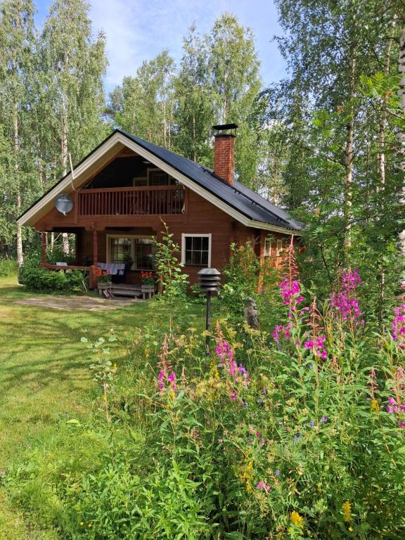 a log cabin with a garden and flowers at Lapikas in Kallo