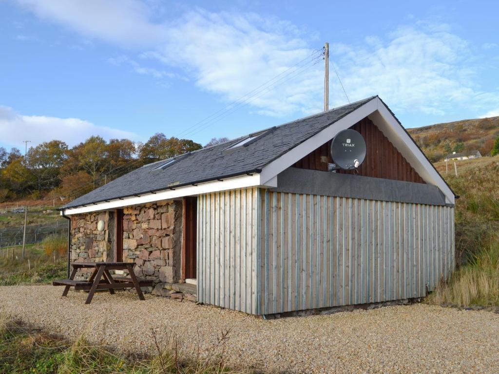 a small building with a black roof and a table at Mango Pony's Bothy - Uk31959 in Dibaig
