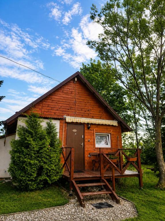 a wooden cabin with a large deck in front of it at Domki POD ŚNIEŻNĄ in Marianówka