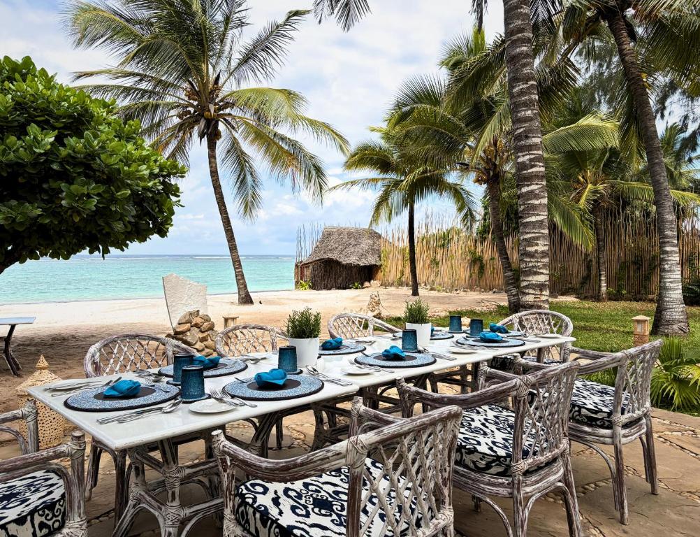 a table on the beach with palm trees and the ocean at Soroi Blue - Diani Beach in Diani Beach