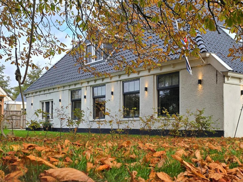 a white house with black windows and a yard at Vakantiewoning In de boerderij in Arum