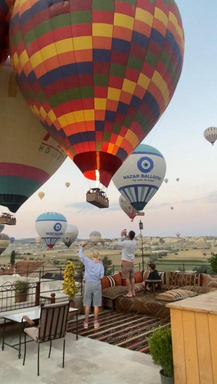Eine Gruppe von Menschen schaut zu Heißluftballons hinauf. in der Unterkunft Sara Cave Cappadocia in Goreme