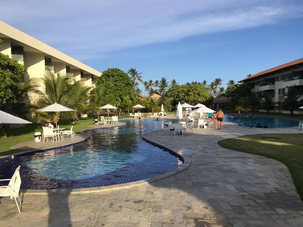 um resort com uma piscina com mesas e cadeiras em Carneiros Beach Resort em Tamandaré