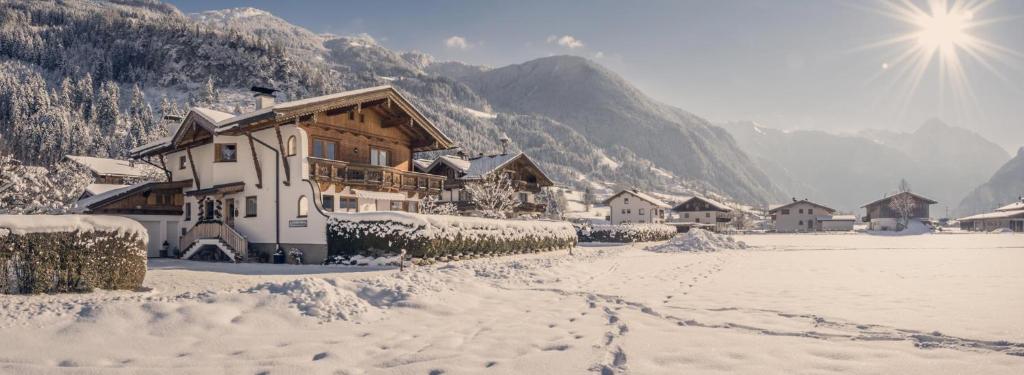 a snow covered village with houses in the mountains at Ferienwohnung Aschenwald in Ramsau im Zillertal
