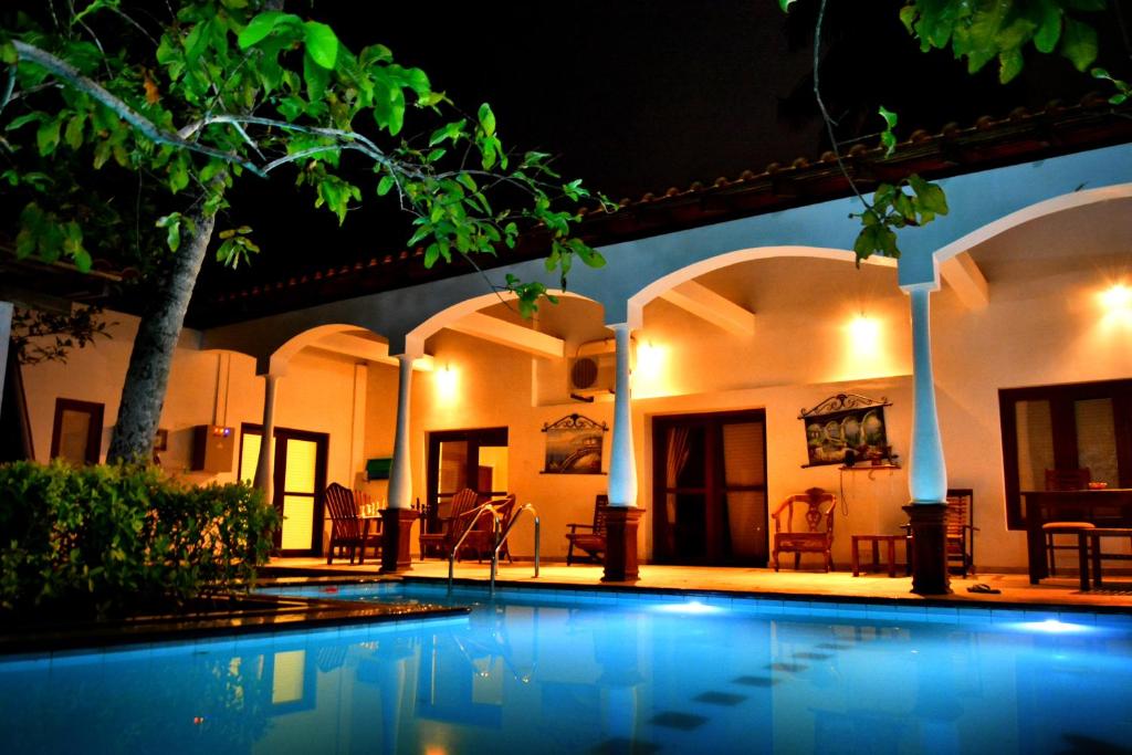 a swimming pool in front of a house at night at Lucas in Bentota