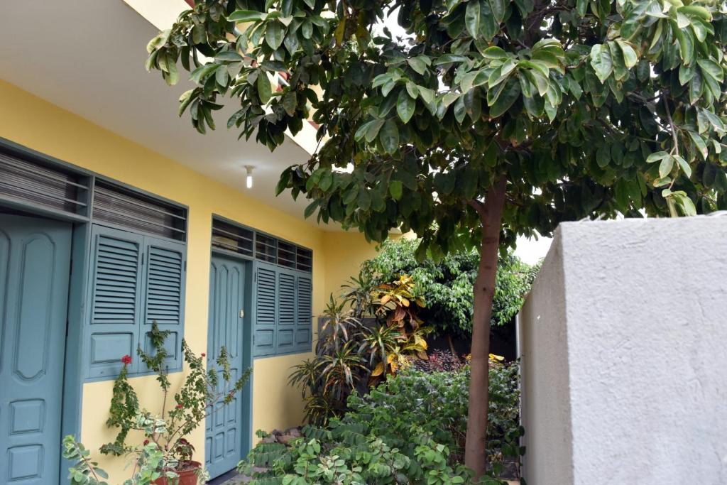 ein gelbes Haus mit blauen Türen und einem Baum in der Unterkunft My Place Apt#1 in Praia