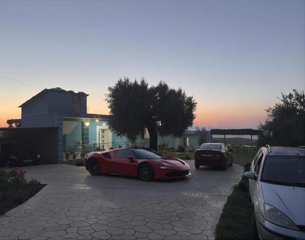 a red car parked in a parking lot next to a house at Rodon Blue Villa in Shetaj