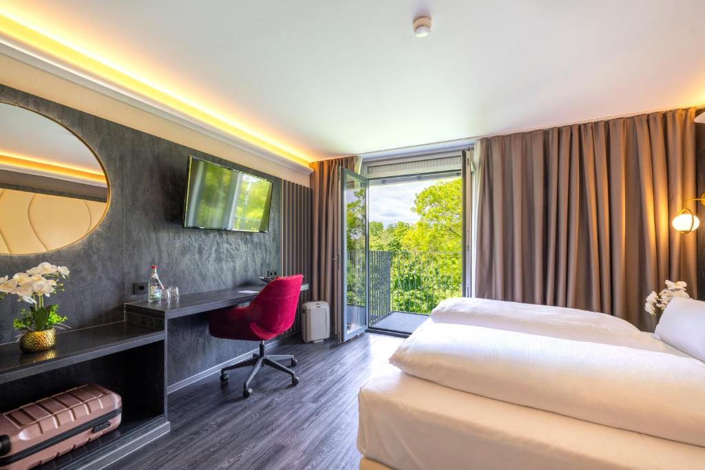 a hotel room with a bed and a desk and a window at PLAZA INN Stuttgart-Ditzingen in Ditzingen