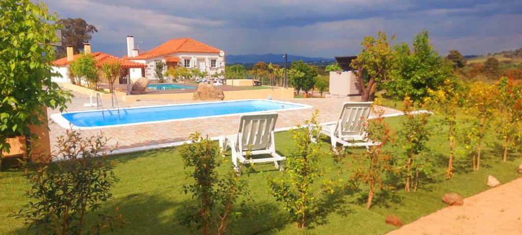 two chairs sitting in the grass near a swimming pool at Quinta Lameira do Vale in Fundão