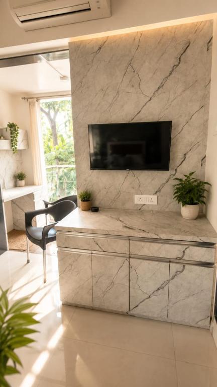 a living room with a tv on a marble wall at LuxeBnb - The Olive Maple Room in Pune