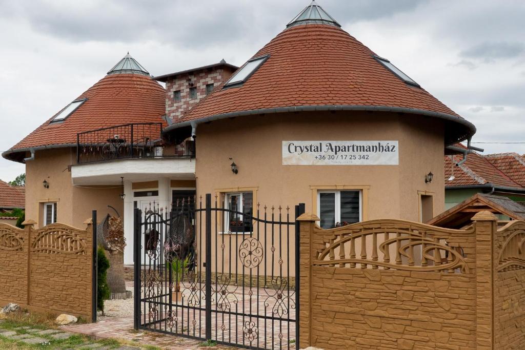 a house with a gate and a building with a roof at Crystalapartmanhaz in Gyula