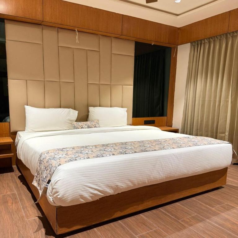 a bedroom with a large bed with white sheets at Centre Point Amravati in Amrāvati